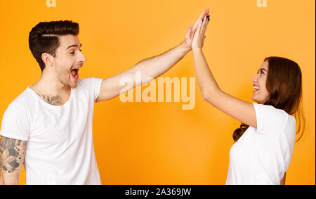 Joyful man and woman greeting each other with high five Stock Photo