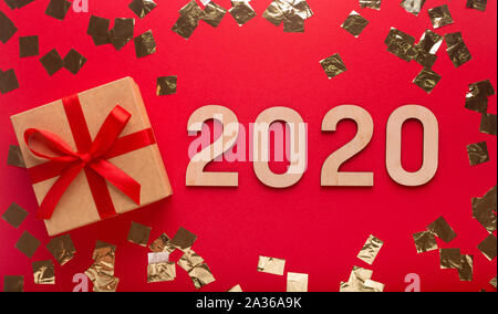 Present box with ribbon on red background with golden confetti Stock Photo