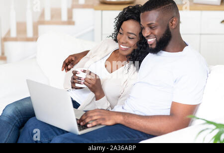 Happy African American man and woman enjoying movie on laptop Stock Photo