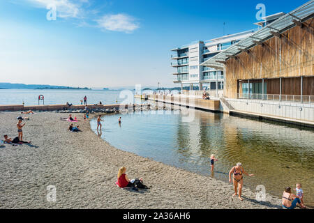 People enjoy a small beach in Aker Brygge district in downtown Oslo Norway.