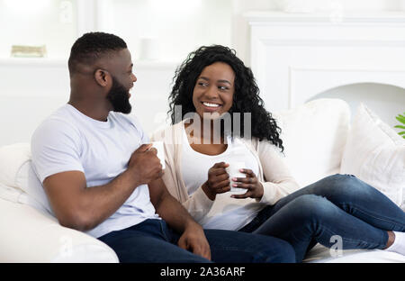 Happy black couple relaxing on couch and drinking coffee Stock Photo