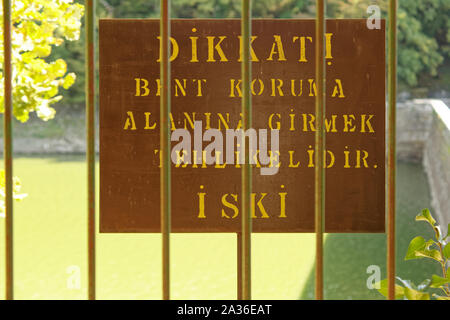 'Danger! Entrance to water reservoir are is dangerous' sign in Turkish language hanged by Iski with bar fences front of it. Stock Photo