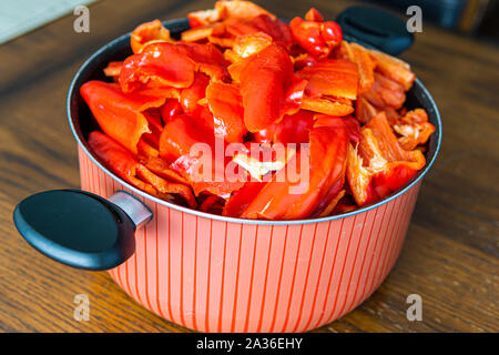 Cut Red Bell Peppers in a pot on a kitchen table Stock Photo