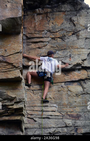 A young male climber works his way up the Amphitheater cliff face on the Ledge Spring Trail at Pilot Mountain State Park in North Carolina. Stock Photo