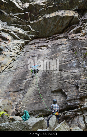 Looking up at a female climber working up the Amphitheater cliff face on the Ledge Spring Trail at Pilot Mountain State Park in North Carolina. Stock Photo