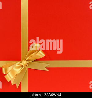 Christmas gift border frame with gold ribbon and bow and red background Stock Photo