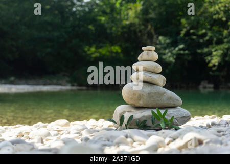 Harmony, balance and simplicity concept. A stone pyramid on the background of river water. Simple poise pebbles, rock zen sculpture, a tower from rive Stock Photo