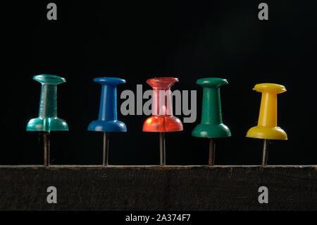 Macro photography of push pin which is pinned on wood with black background at studio Stock Photo