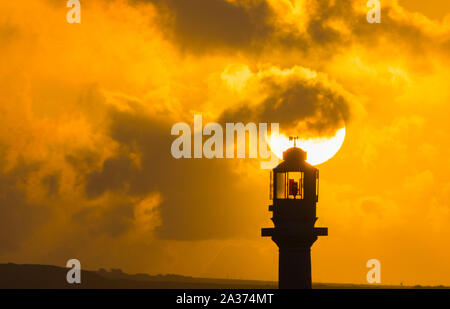 Penzance, Cornwall, UK. 6th October 2019. UK Weather.  The sun rises behing the lighthouse at Penzance Harbour. Credit Simon Maycock / Alamy Live News. Stock Photo