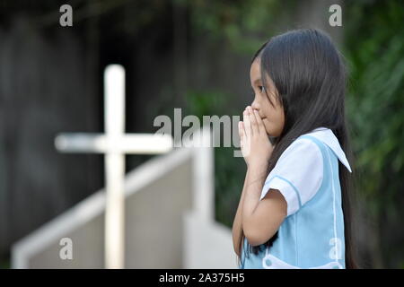 Filipina Juvenile In Prayer And Cross Stock Photo