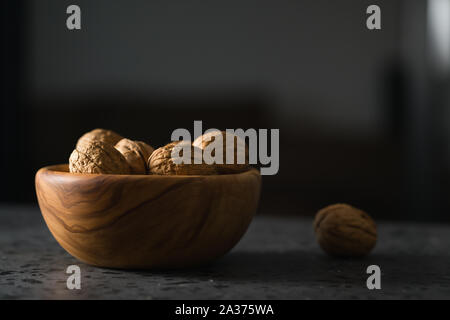 inshell walnuts in olive wood bowl on terrazzo countertop, shallow focus Stock Photo