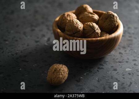 inshell walnuts in olive wood bowl on terrazzo countertop, shallow focus Stock Photo