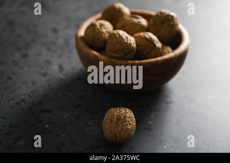 inshell walnuts in olive wood bowl on terrazzo countertop, shallow focus Stock Photo