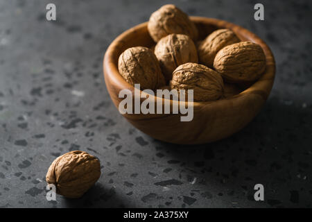 inshell walnuts in olive wood bowl on terrazzo countertop, shallow focus Stock Photo