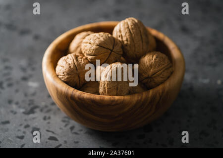 inshell walnuts in olive wood bowl on terrazzo countertop, shallow focus Stock Photo