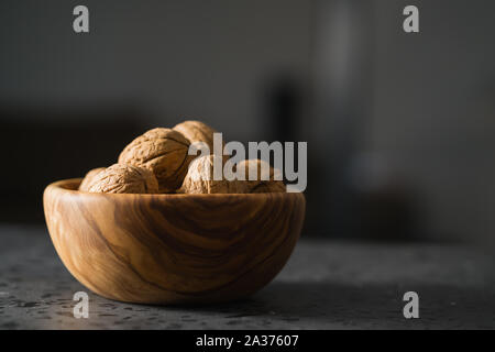 inshell walnuts in olive wood bowl on terrazzo countertop, shallow focus Stock Photo
