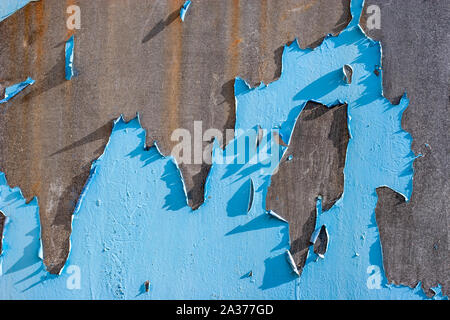 Abstract background. Rusty metal surface with old peeled blue paint. Torn paint hangs in places. Stock Photo