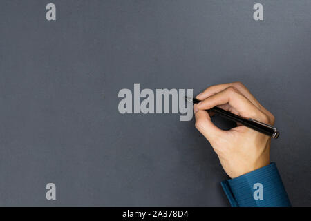 A businessman hand holding black pen and write something on chalkboard. Stock Photo