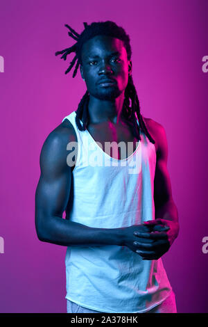 serious unhappy guy keping hands together looking at the camera, close up portrait isolated violet background Stock Photo
