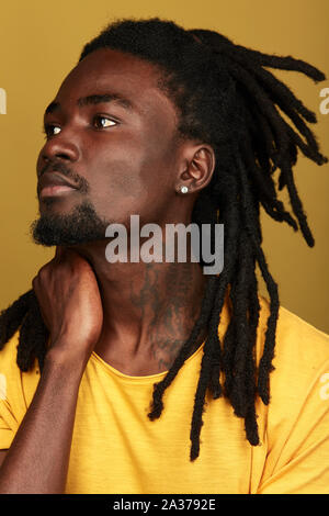 african guy suffering from pain in the neck, close up side view photo. desease, illness. close up portrait, isolated yellow background Stock Photo