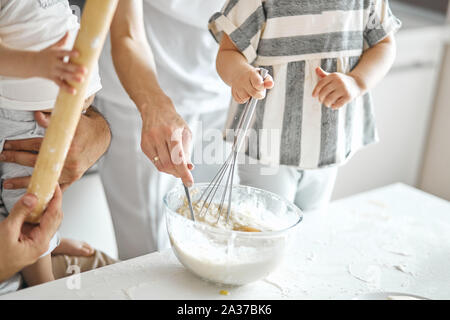 children mixing pastry in the kitchen, helping parents to bake a cake.close up cropped photo Stock Photo
