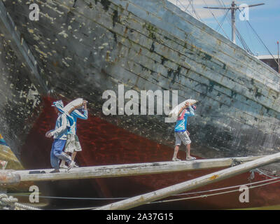 Jakarta, Indonesia - July 13, 2009: unskilled workers loading sacks with cement onto a wooden transport vessel4 Stock Photo