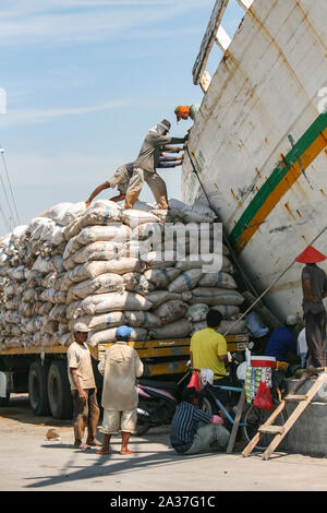 Jakarta, Indonesia - July 13, 2009: unskilled workers loading sacks from a truck onto a wooden transport vessel Stock Photo