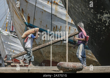 Jakarta, Indonesia - July 13, 2009: unskilled workers loading sacks with cement onto a wooden transport vessel4 Stock Photo