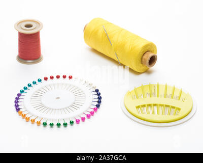 Coils with red and yellow threads with a needle, a set of pins and needles, on a white background Stock Photo