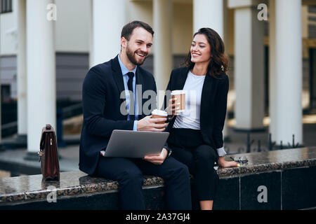 young office workers sitting outdoors and entertaining each other, close up photo Stock Photo