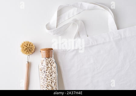 Glass jar, wooden brush and shopping bag on white background. Zero waste concept. Kitchen background with no plastic utensils Stock Photo