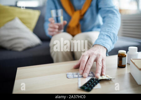 Close up of unrecognizable senior man reaching for pills, focus on foreground, copy space Stock Photo