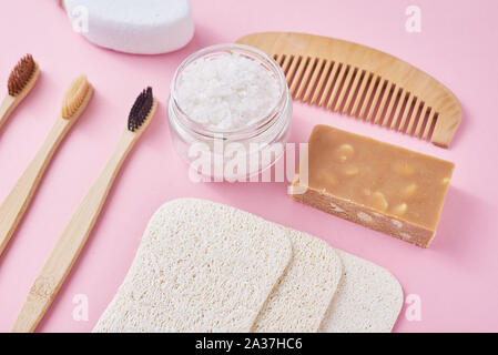 Set of eco friendly personal hygiene objects on pink background. Bamboo toothbrush, wooden comb, sponge, soap and sea salt, top view flat lay. Zero wa Stock Photo