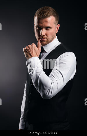 businessman in elegant shirt, vest, tie with hand on chin making decision. close up portrait, isolated black background, studio shot. Stock Photo