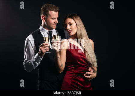 young romantic people spending time at nighclub, clinking glasses. isolated black background. St.Valentine's day Stock Photo