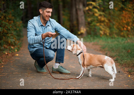 smiling handsome owner stroking dog, full length side view photo.animal lover Stock Photo