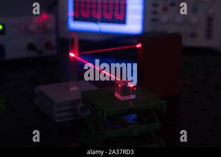 Experiment in optic lab with laser device. Red laser on optical table in physics laboratory Stock Photo