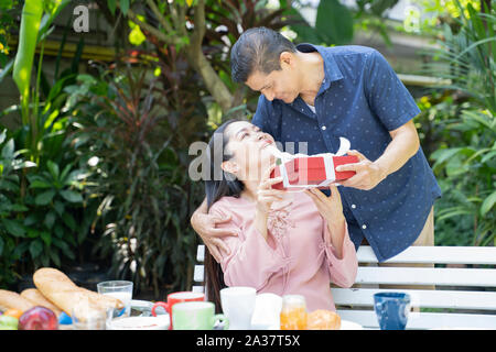 Asian man surprising woman in special day. Family and Lovers concept. Birthday and Valentine theme. Stock Photo