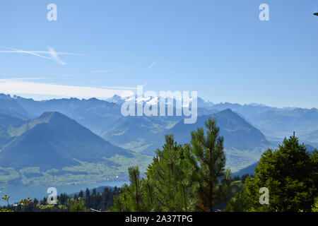 Panoramic landscape view of meadows, mountain ranges and snowy mountain peaks from the top of Rigi Kulm, Mount Rigi in Switzerland Stock Photo