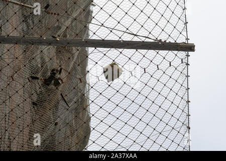 fallen rock caught in overhead wire safety netting above a road - Spain, Europe Stock Photo