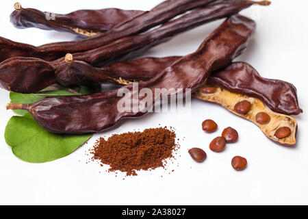 Carob beans. Healthy organic sweet carob pods with seeds and leaves on white background Stock Photo