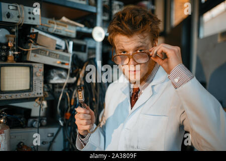 Strange engineer holds electric tube in laboratory Stock Photo