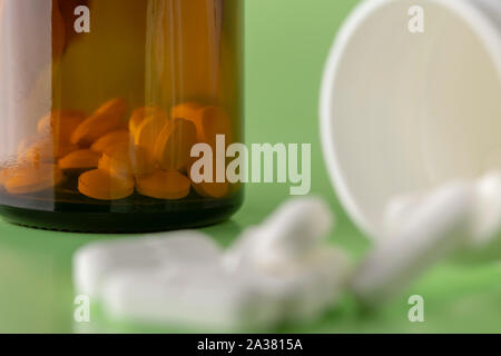Various plastic and glass medicine bottles and white tablets around on a colored background Stock Photo