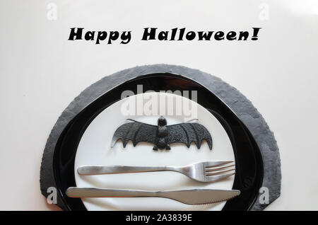 Elegant Halloween place settings in black white colors, silver cutlery,line napkin and ring with  bat. Happy Halloween party concept. Stock Photo