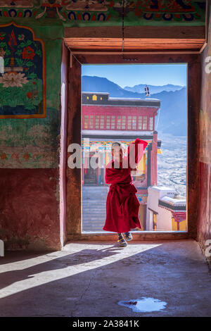 A young monk going through a door at Thiksey Monastery, Ladakh, India Stock Photo