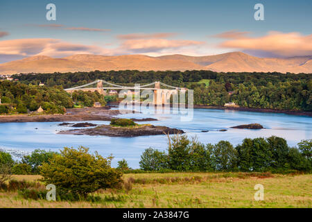 A view of the Menai Bridge from Anglesey looking across the Menai Strait towards the Wales mainland & the mountain range of Snowdonia National Park. Stock Photo