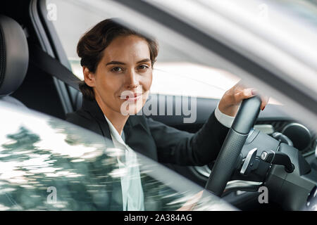 Side view of businesswoman driving car looking out of window. Portrait of a woman going to office in her car. Stock Photo
