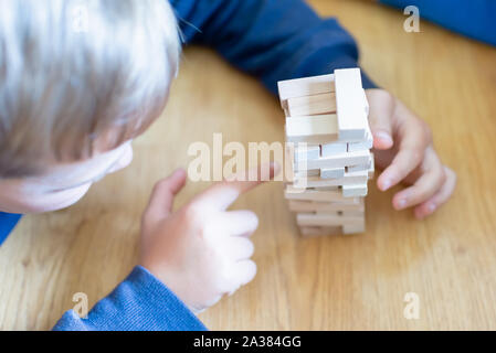 Close up couple playing jenga indoor on table.Boy lying down and playng. Stock Photo