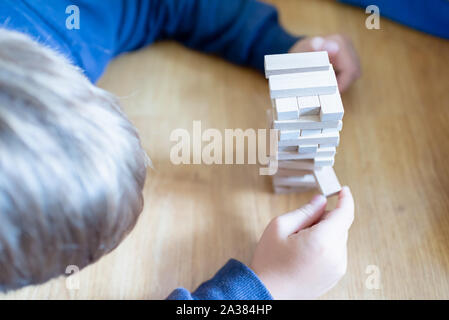 Close up couple playing jenga indoor on table.Boy lying down and playng. Stock Photo