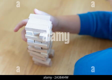 Close up couple playing jenga indoor on table.Boy lying down and playng. Stock Photo